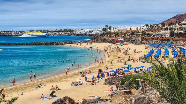 playa dorada en playa blanca resguardada del viento con gente al fondo